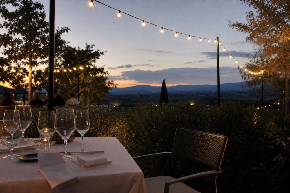 A set table with wine glasses on a hotel restaurant terrace at dusk, no text, no logos, no people